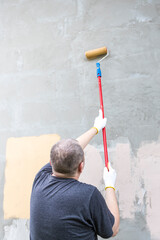 Wall Mural - A man is painting a wall with a roller