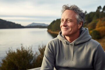 Wall Mural - Portrait of a happy man in his 50s dressed in a comfy fleece pullover on serene lakeside view