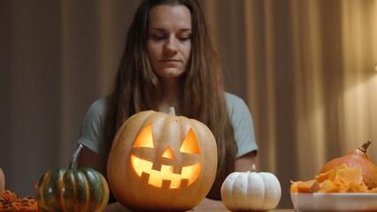 Wall Mural - A Family Evening in a Cozy Home Setting, a Woman Shows a Newly Carved Jack-O'-Lantern for Halloween. Pumpkins on the Table.