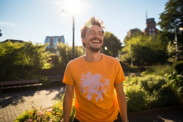 Wall Mural - Portrait of a joyful man in his 20s dressed in a casual t-shirt isolated in vibrant city park