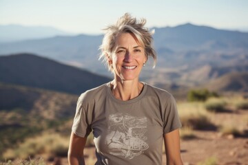 Wall Mural - Portrait of a blissful woman in her 50s sporting a vintage band t-shirt while standing against panoramic mountain vista