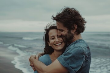 Wall Mural - Portrait of a smiling couple in their 30s sharing a hug on the seashore