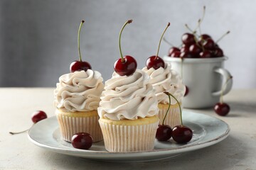 Wall Mural - Delicious cupcakes with cream and cherries on light textured table, closeup