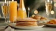 © JP STUDIO LAB - A birthday brunch with a beautifully set table, mimosas, and a stack of pancakes with candles on top