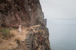 © Milou Dirks - art portrait of asian woman standing in long white dress on rock and cliff in the mountains near ocean on Madeira island