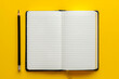 © Sebelas Studio - A blank notebook with white lined pages and black pencils on the left side of it, placed against a vibrant yellow background