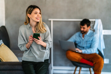 Wall Mural - Smiling young woman chatting in social networks, working, using mobile applications at home.