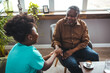 © Dragana Gordic - A black mid-adult nurse provides attentive care to a senior black male, ensuring comfort in a cozy home environment while engaging in a supportive conversation.