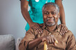© Dragana Gordic - A black mid-adult nurse provides gentle support to a senior black man holding a cane, depicting home healthcare services.