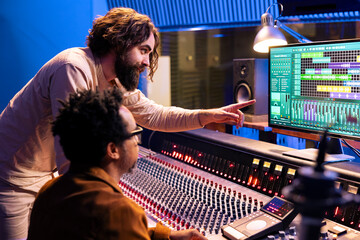 Aufkleber - Young performer working on new album with his record producer in studio, processing sounds and mixing them in post production. Musician collaborating with audio expert to edit recorded music.