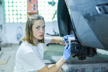 Wall Mural - female auto mechanic repairs car brake system