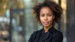 © WS Studio 1985 - Confident Leader: A portrait of a young Black woman with arms crossed, exuding confidence in the urban landscape.