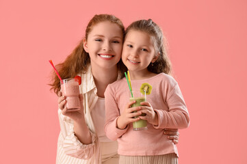 Canvas Print - Smiling mother and little daughter with glasses of smoothie on pink background