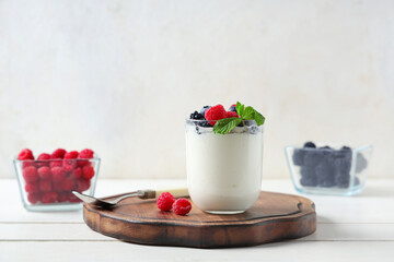 Wall Mural - Glass of tasty yogurt with different fresh berries on white wooden background