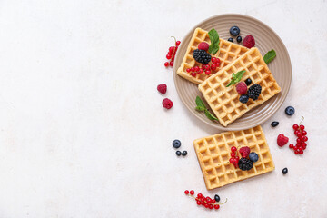 Wall Mural - Plate of sweet Belgian waffles with different fresh berries and mint on white background