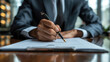 © zeenika - Close-up of a businessman in a suit signing a contract at an office desk with a fountain pen emphasizing professionalism and business.