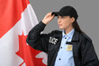 © Pixel-Shot - Female police officer and flag of Canada on grey background
