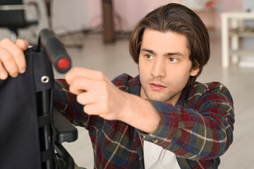 Wall Mural - Young man repairing his wheelchair at home, closeup