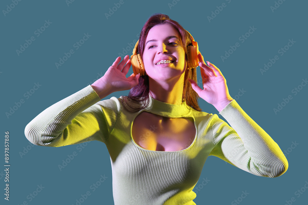Young woman with headphones dancing against blue background