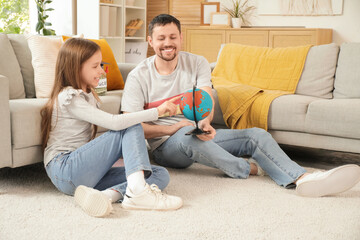 Poster - Father and his daughter with globe and money jar choosing country for education at home. Tuition fees concept