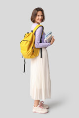 Canvas Print - Beautiful female student with backpack and books on grey background