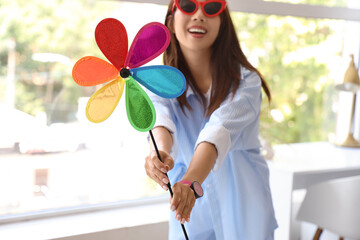 Wall Mural - Young woman in sunglasses with toy windmill at home, closeup