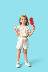 Poster - Cute little happy girl with bottle of detergent and brush showing thumb-up gesture on blue background