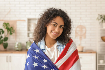 Wall Mural - Happy young African-American woman with USA flag at home