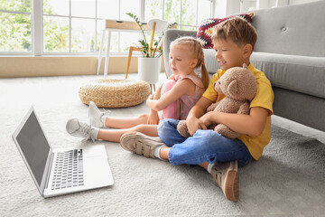 Wall Mural - Cute little children watching cartoons on laptop at home