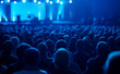 © Curioso.Photography - Audience attending a conference with blue lighting and large screens.