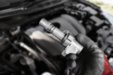 A mechanic hand holds an ignition coil for a spark plug of a car engine , Automotive parts concept