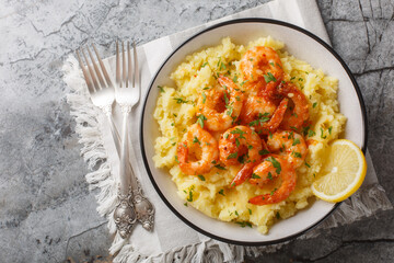 Canvas Print - Portion of garlic shrimps with mashed potatoes, lemon and herbs close-up in a bowl on the table. Horizontal top view from above