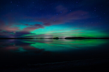 Wall Mural - northern lights dancing over calm lake in farnebofjarden national park in north of sweden.