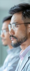 Wall Mural - Two men wearing glasses are sitting next to each other. One of them has a beard and is wearing a suit