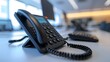 © Munali - A close-up of a modern black desk telephone positioned on a minimalist office workspace, symbolizing professional communication and technology.