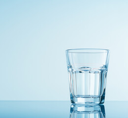 Wall Mural - A glass of water and a glass bottle stands on the surface of blue water