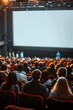 © pornsawan - People in the cinema auditorium with Cinema blank wide screen and red chairs in the cinema hall,People silhouettes watching movie performance,empty white screen,space for text.
