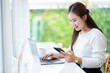 © Thinapob - asian freelance people business female read writing message on smartphone using casual working with laptop computer for browsing internet, chatting and blogging and smartphone,notebook in coffee shop.