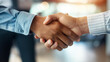 © Hanna - Handshake of people in formal suits in the office. Two hands shake hands against a blurry office background. Office and business, work job, agreement and partnership