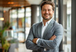 © PixelGallery - Successful Executive Posing in Bright Workplace. A vibrant photo of a man in a grey blazer, exuding confidence and success in a well-lit, modern office environment.