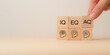 © Parradee - Wooden blocks with the letters IQ, EQ and AQ representing Intelligence Quotient, Emotional Quotient, Adaptability Quotient. A hand adjusting AQ block, symbolizing adaptability in modern intelligence.