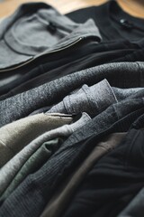 Wall Mural - Stack of black and grey t-shirts and sweaters rests on a wooden table