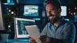 © Maciej Koba - Happy man using tablet computer in a modern tech office.