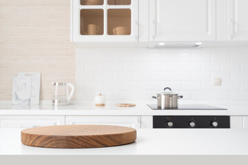 Wall Mural - Round wooden pedestal on white table with copy space and defocused kitchen counter background