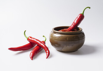 Wall Mural - Close-up of three raw red peppers on white floor with one in red pepper paste on a jar, South Korea
