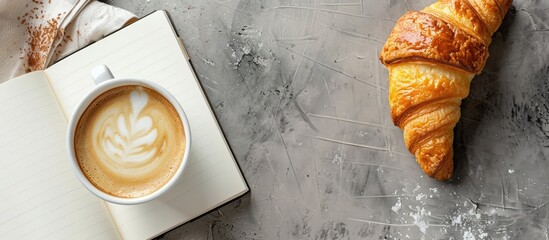 Poster - Top view of a cup of coffee croissant and a white book on a table with additional copy space for images