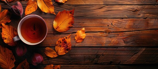 Fototapete - Autumn leaves decorate a wooden background next to a cup of tea providing a cozy vibe in an inviting copy space image