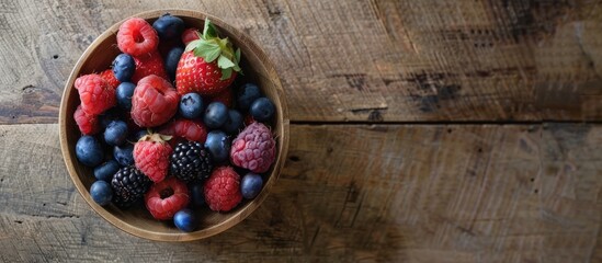 Wall Mural - Assorted summer berries displayed in a bowl on a quaint wooden table with ample copy space image