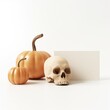 © vstudio - two orange pumpkins next to human skull with blank festive empty greeting white card on light background festival celebration holiday