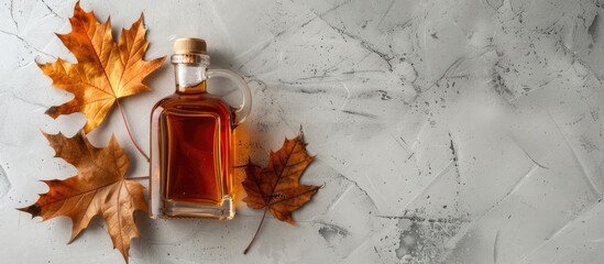 Aufkleber - Flat lay composition featuring a delicious bottle of maple syrup a dry leaf and a light grey table with ample copy space image